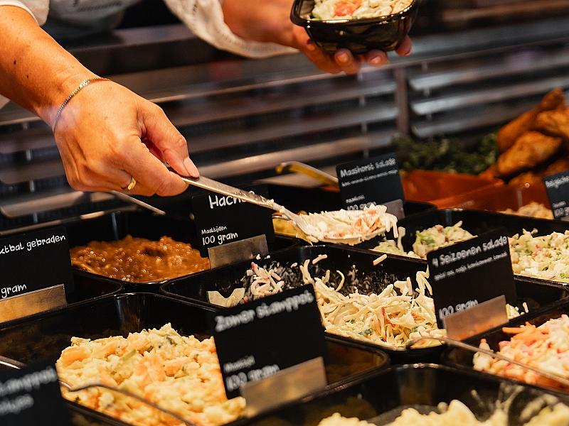 Versspecialist schept salade in bakje